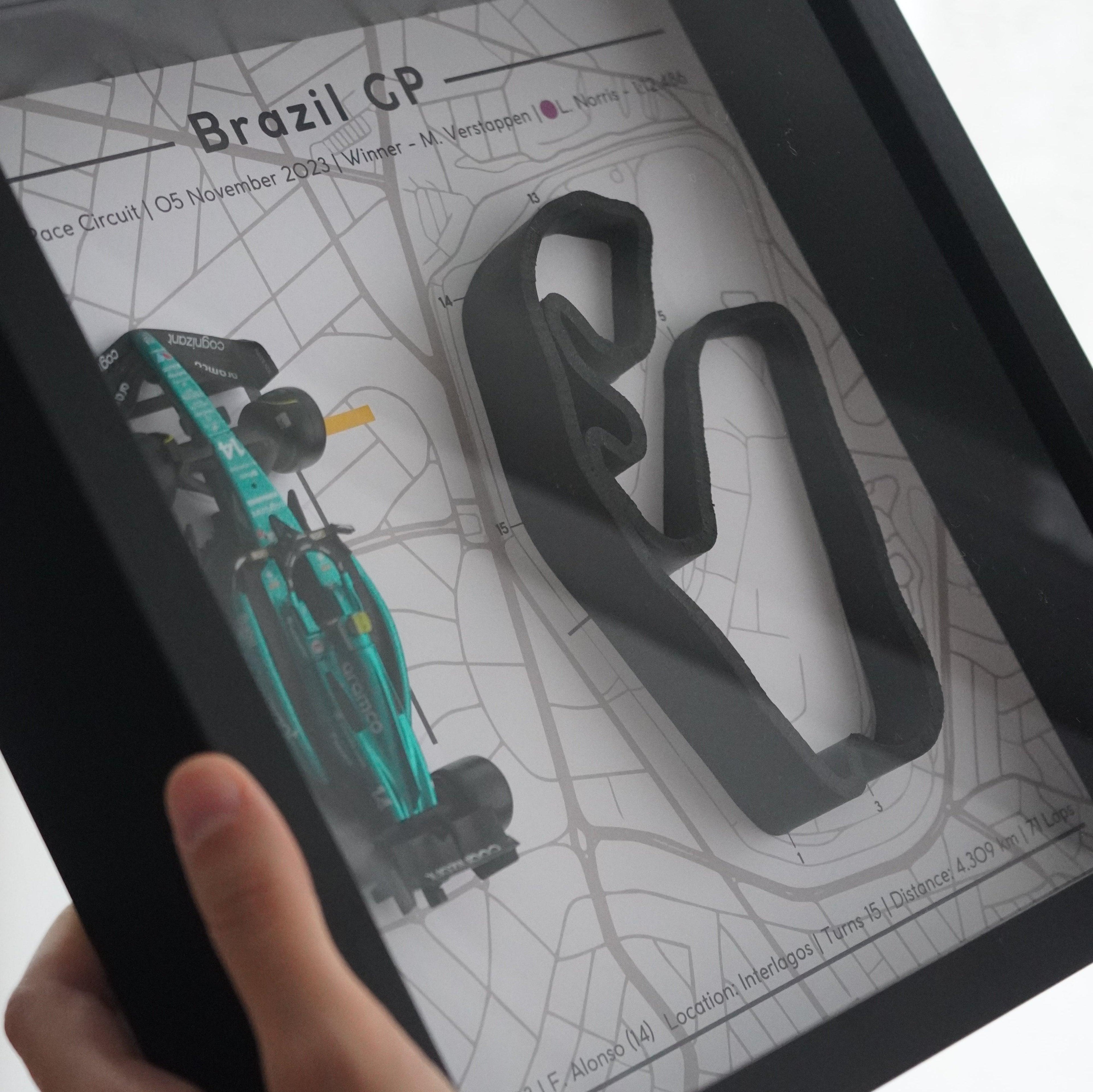 F1-themed frame featuring a 1:43 scale Alonso's car on the Brazil GP track. Includes a 3D-printed track replica with real elevation changes and a satellite map background.