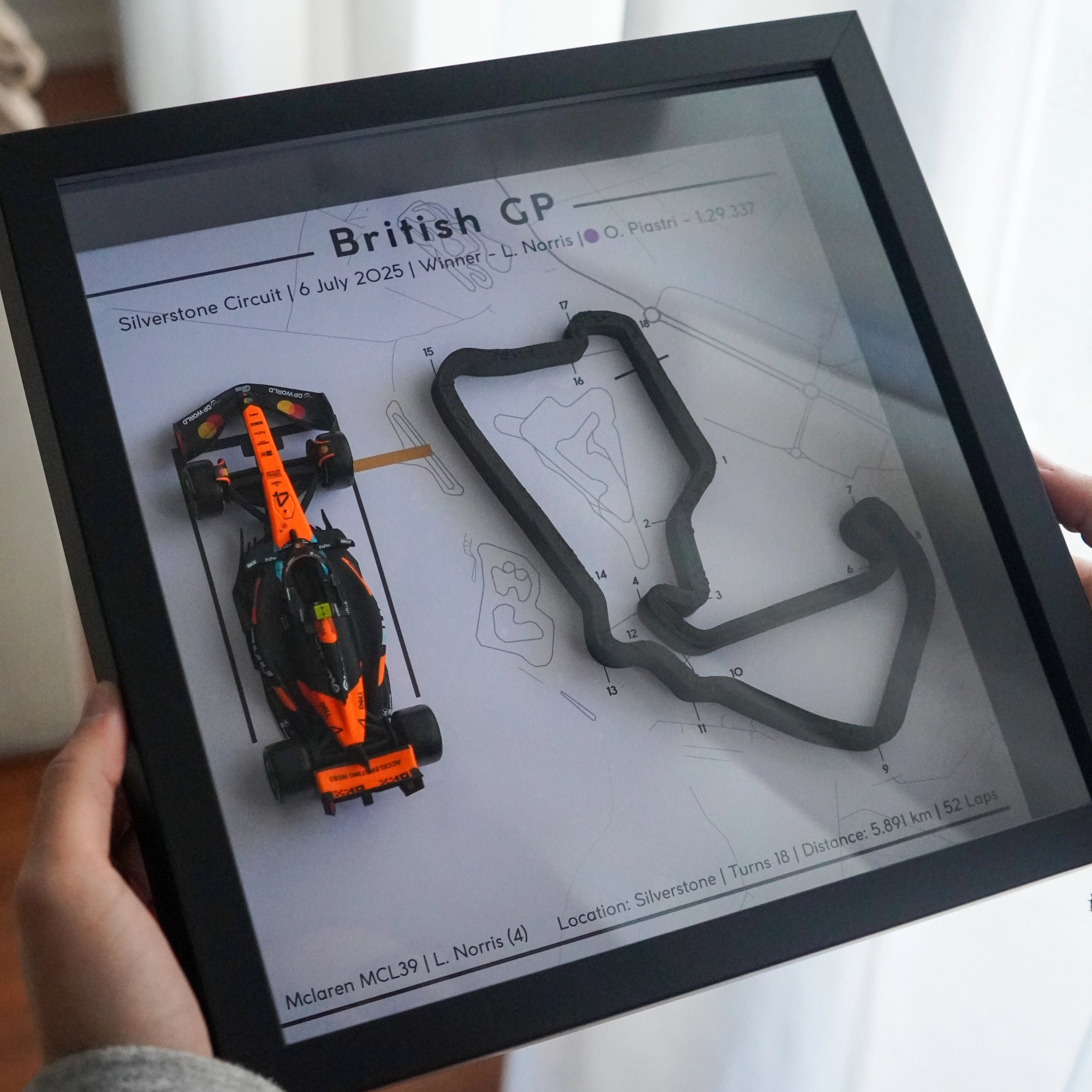 Person holding a tablet displaying a Formula 1 car and track layout.