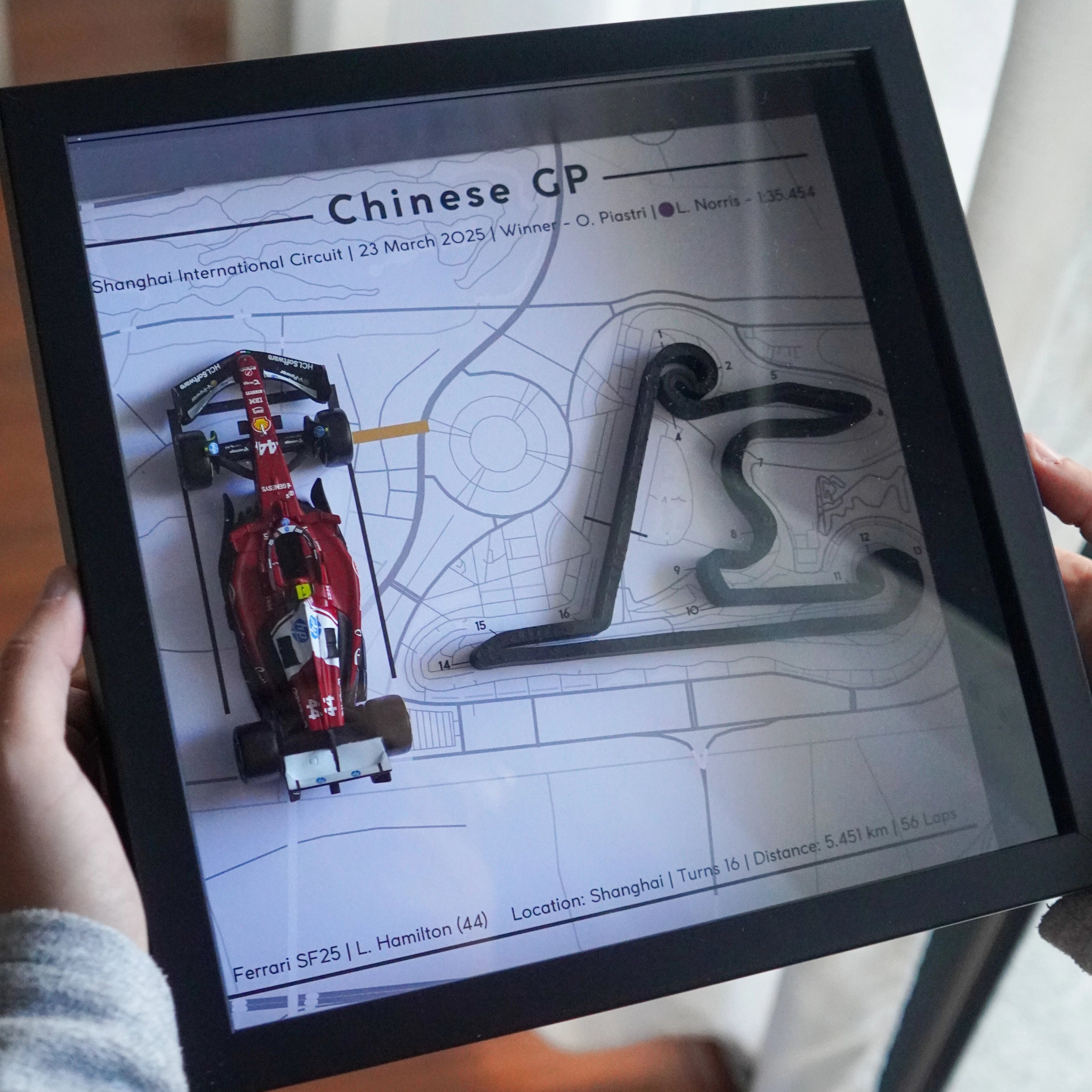 Person holding a tablet displaying a Formula 1 track layout with 'Chinese GP' text.
