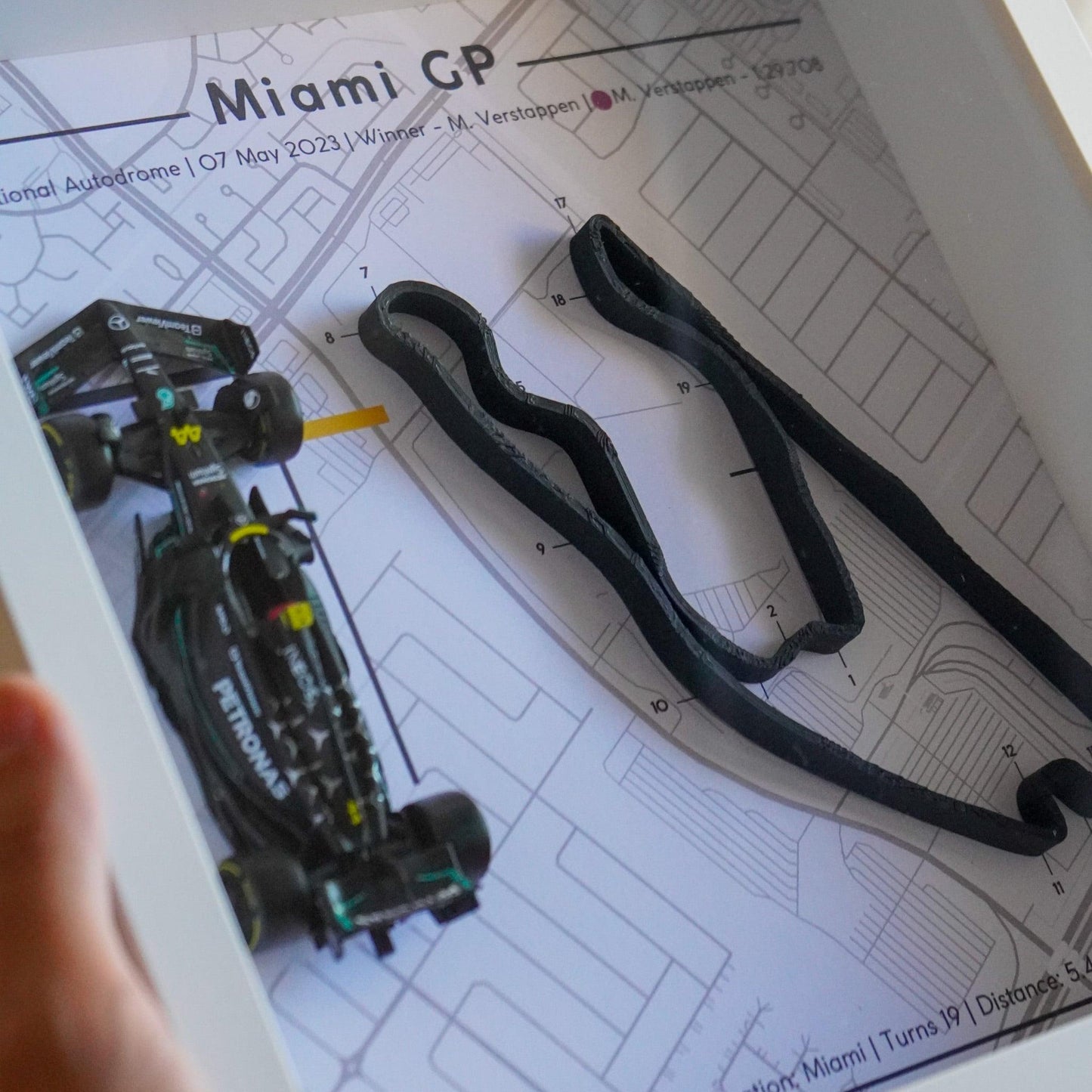 F1-themed frame featuring a 1:43 scale Hamilton's car on the Miami GP track. Includes a 3D-printed track replica with real elevation changes and a satellite map background