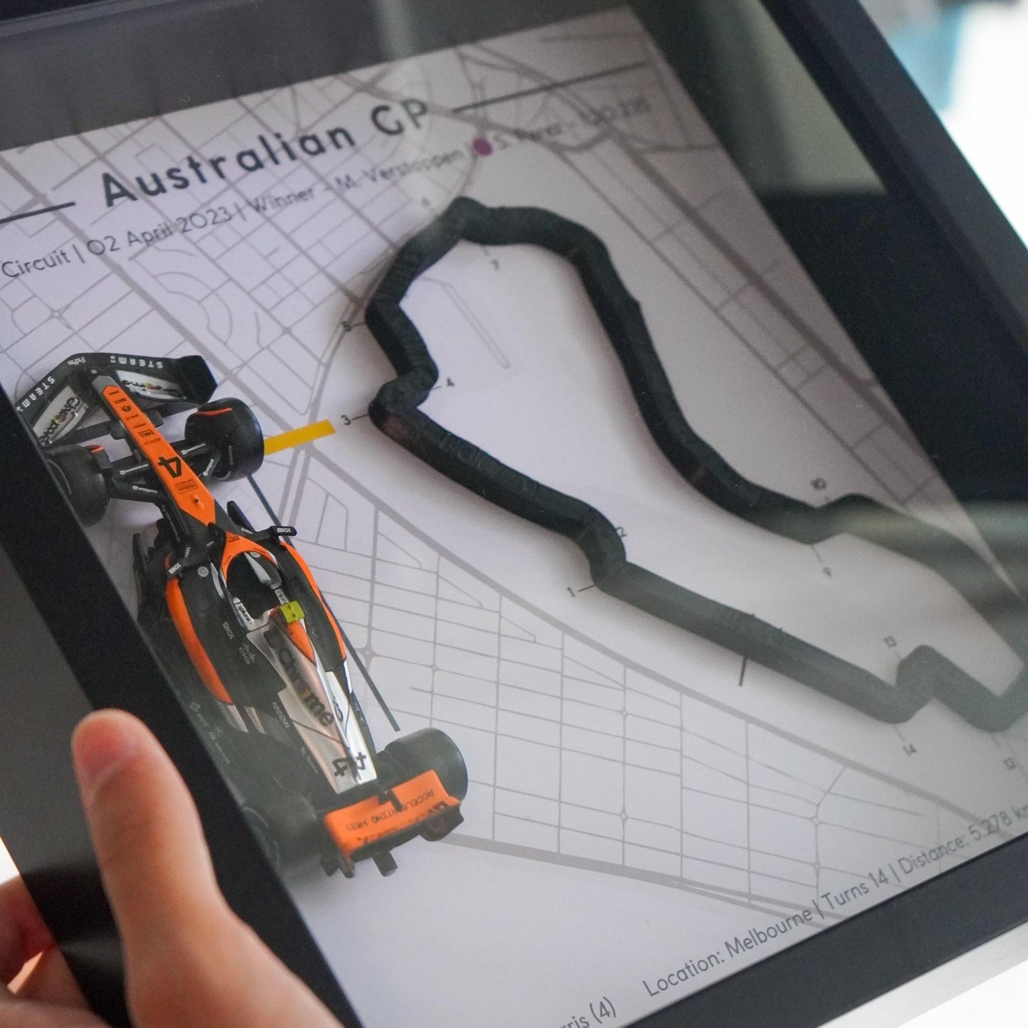 F1-themed frame featuring a 1:43 scale Norris's car on the Australian GP track. Includes a 3D-printed track replica with real elevation changes and a satellite map background