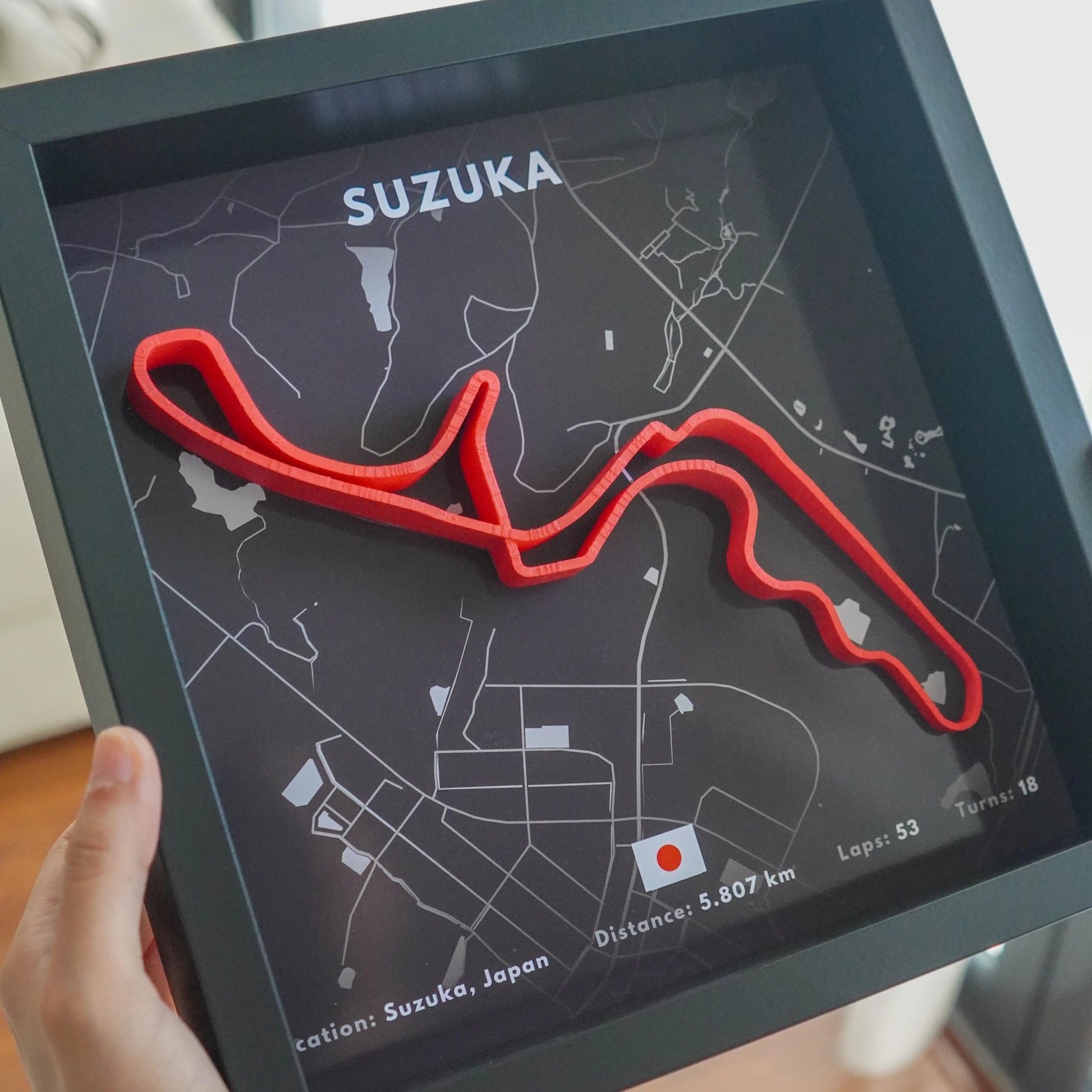 Red track model on a map of Suzuka Circuit with 'Suzuka' branding.