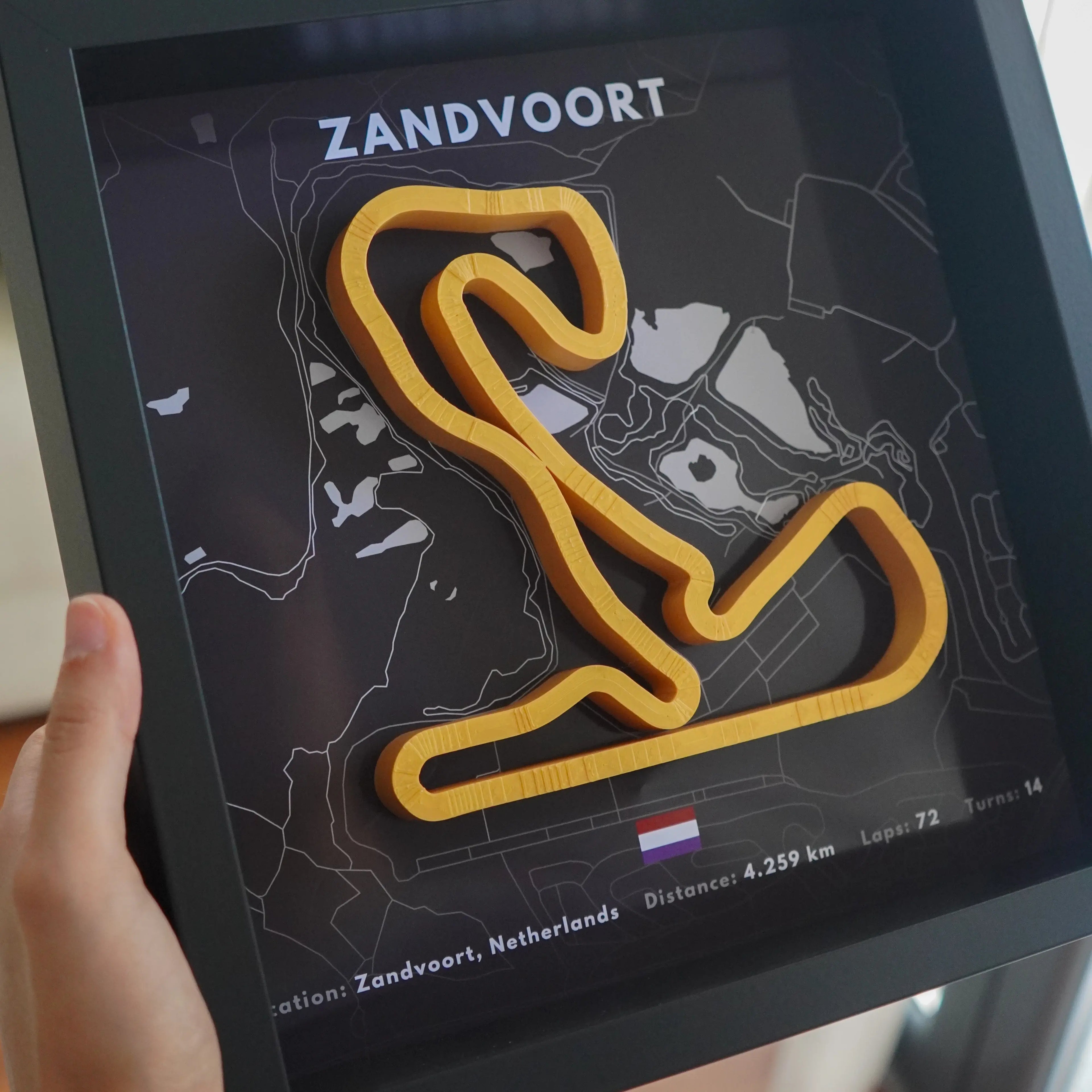 Framed map of Zandvoort racetrack with a hand holding it.